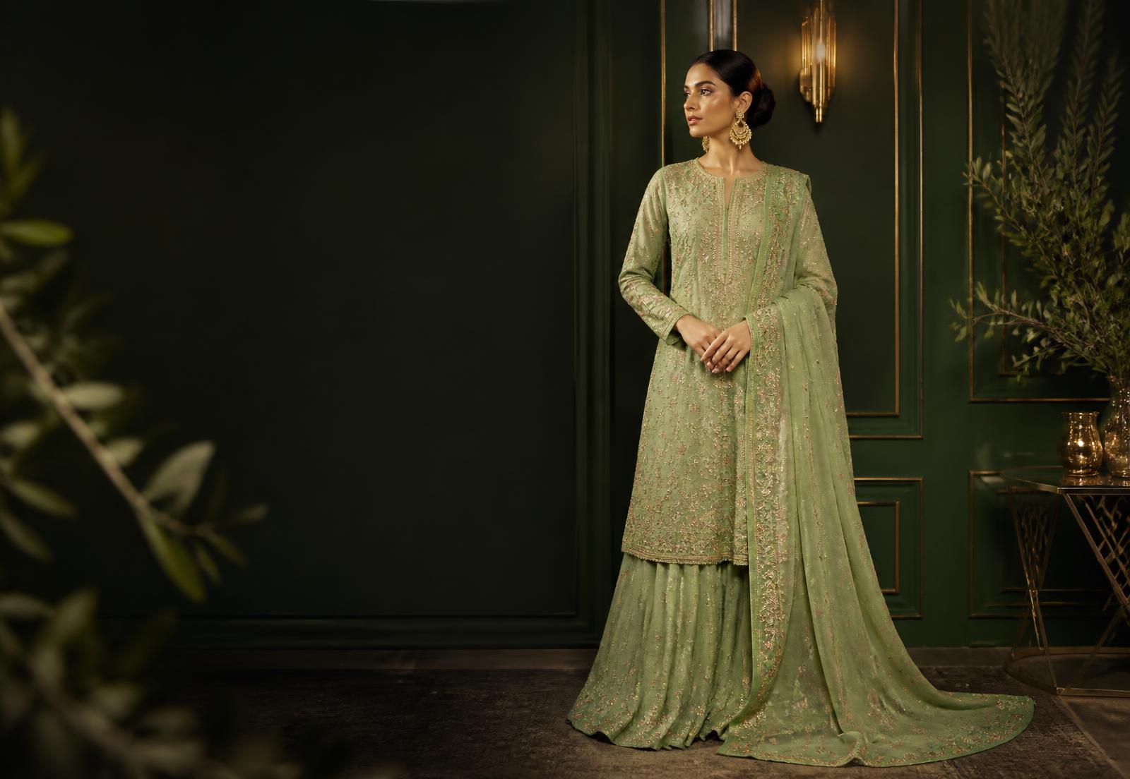 Model wearing an embroidered pistachio green Pakistani outfit in a luxury boutique
